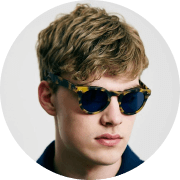 A young man wearing sunglasses and a blue shirt.